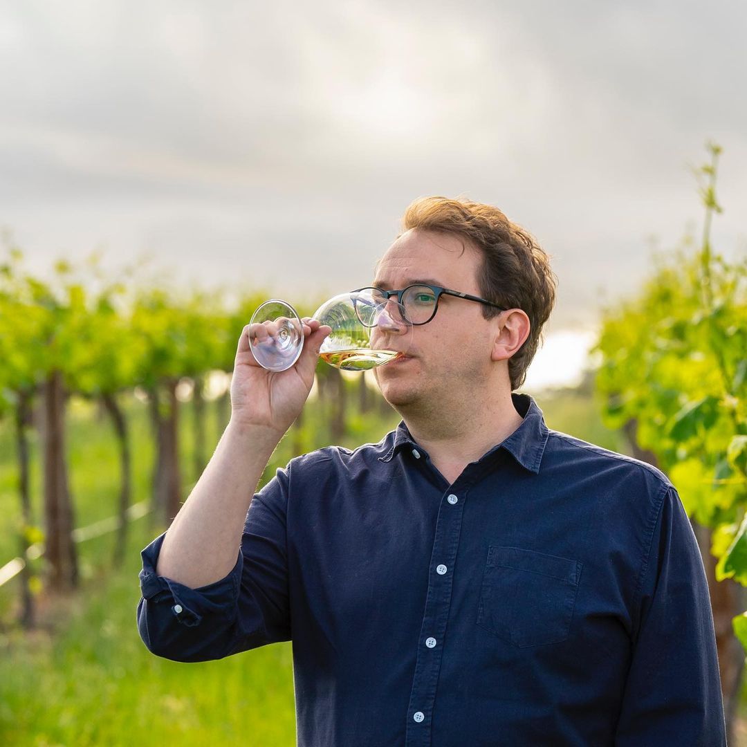 Tom Shanahan, winemaker, sipping a glass of wine in a vineyard
